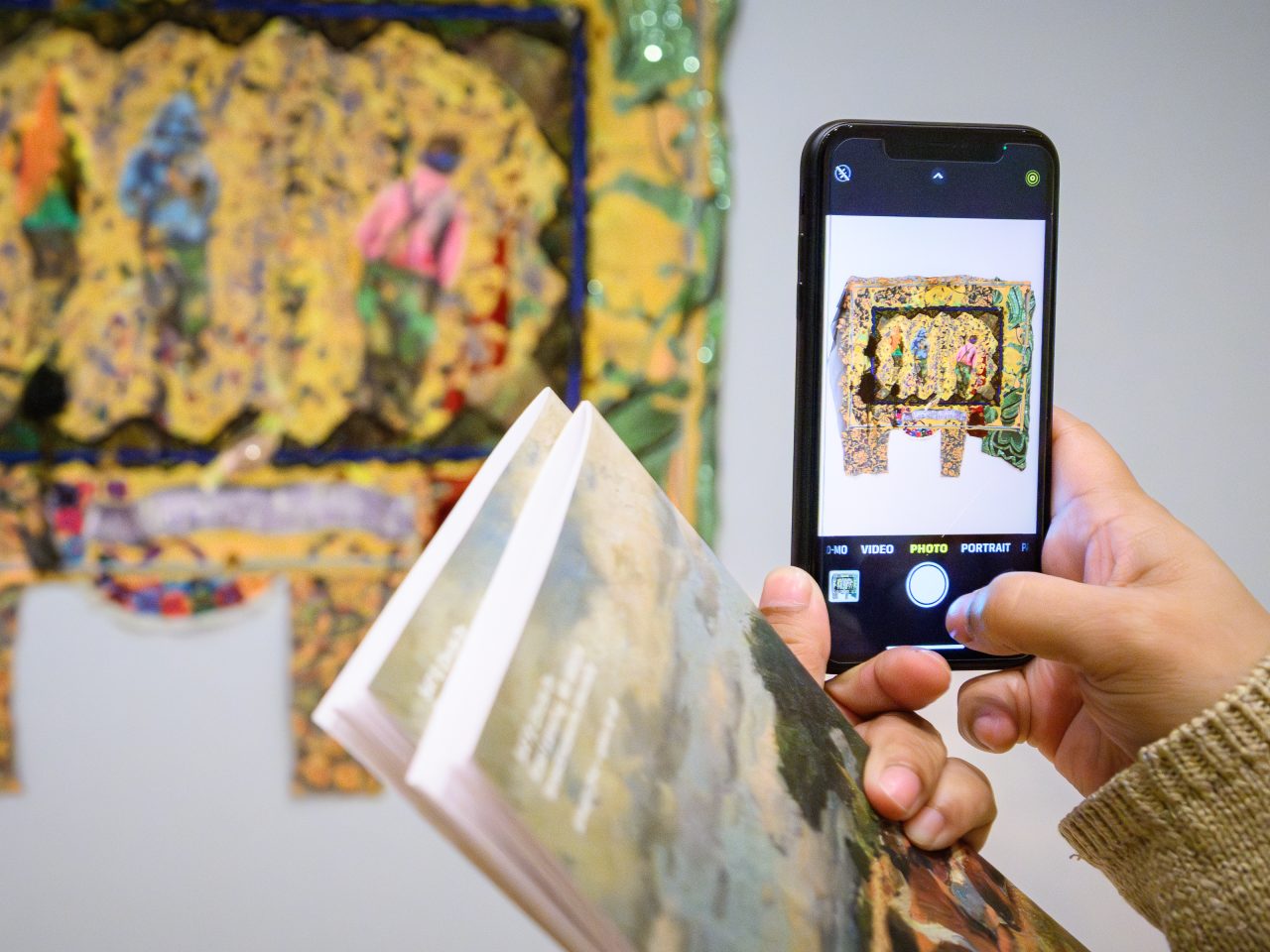 A picture of someone taking a picture of art hanging on the wall